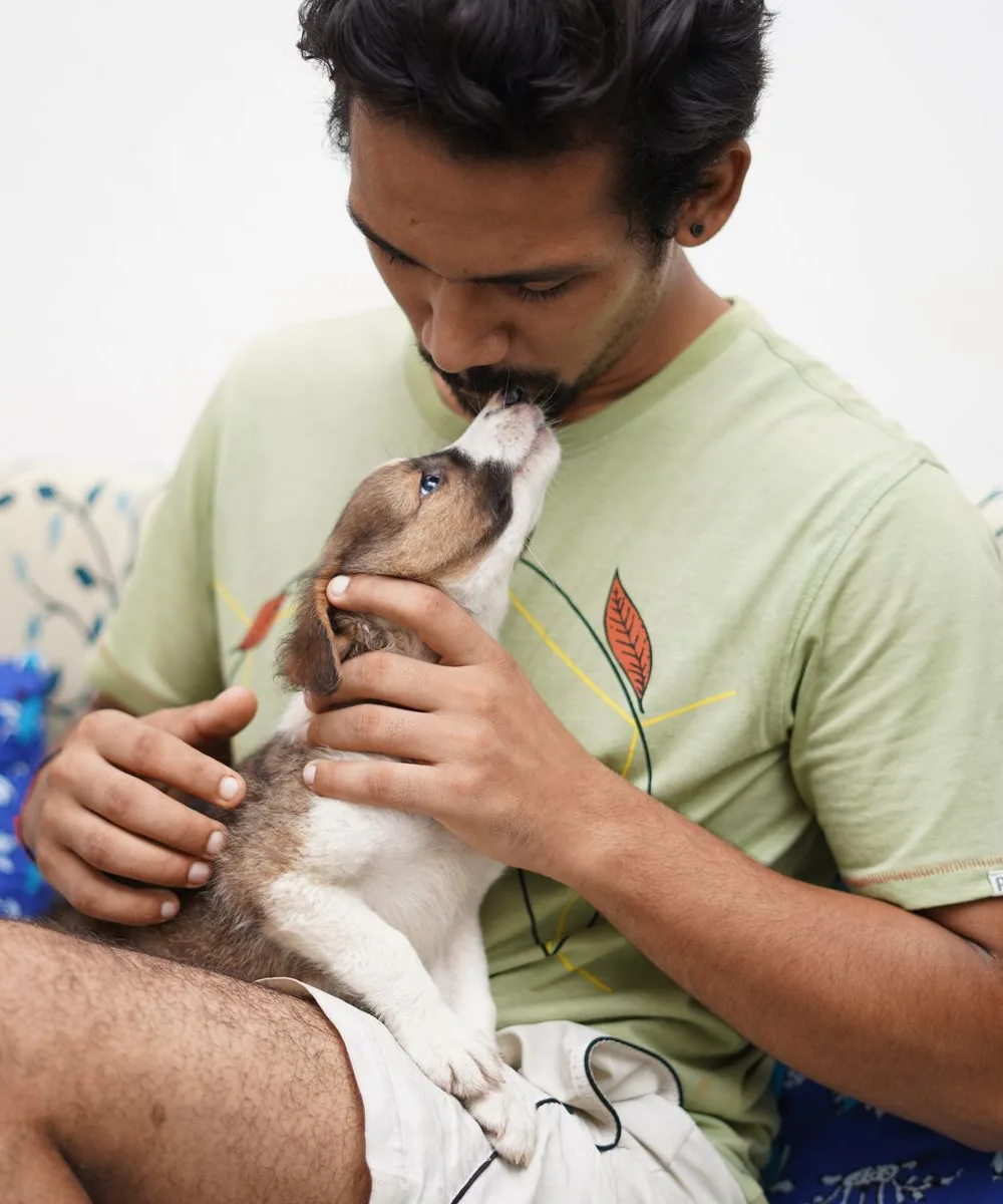 Un hombre abraza con cuidado a un cachorro sentado en el sofá de su casa.